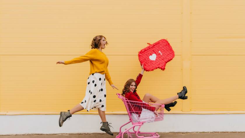 Two best friends fooling around on the street. Full length shot of girls with internet icon